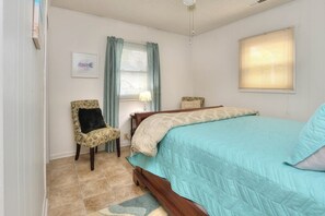 A bedroom with a bed, a chair, a lamp, and a window.
