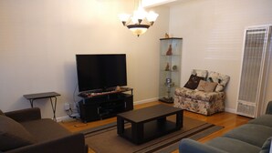 Una sala de estar con una televisión de pantalla plana, una mesa de centro y dos sofás.