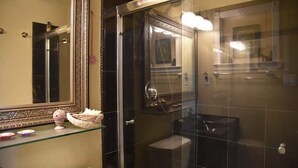 Un baño con cabina de ducha de vidrio, un inodoro y un lavabo con espejo.