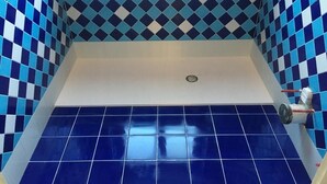 Un baño con baldosas azul y blanco a cuadros, una bañera blanca y un desagüe visible.