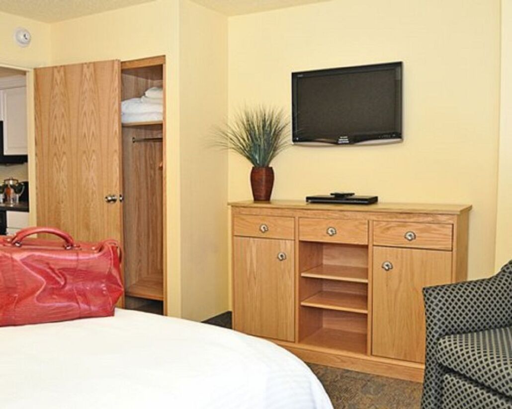 Ein Hotelzimmer mit einem Bett, einem Holzschrank, einem Fernseher und einem kleinen Tisch mit einer Pflanze.