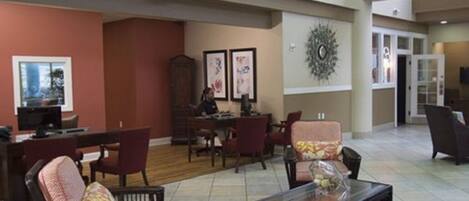 A spacious lobby with comfortable seating, a reception desk, and framed artwork on the walls.