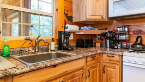 A kitchen with wooden cabinets, a granite countertop, a sink, a stove, and various kitchen appliances. - Climber`s Haven- Hot Tub, Firepit, Sunroom, WiFi, 5 mins to Natural Bridge (Rogers)
