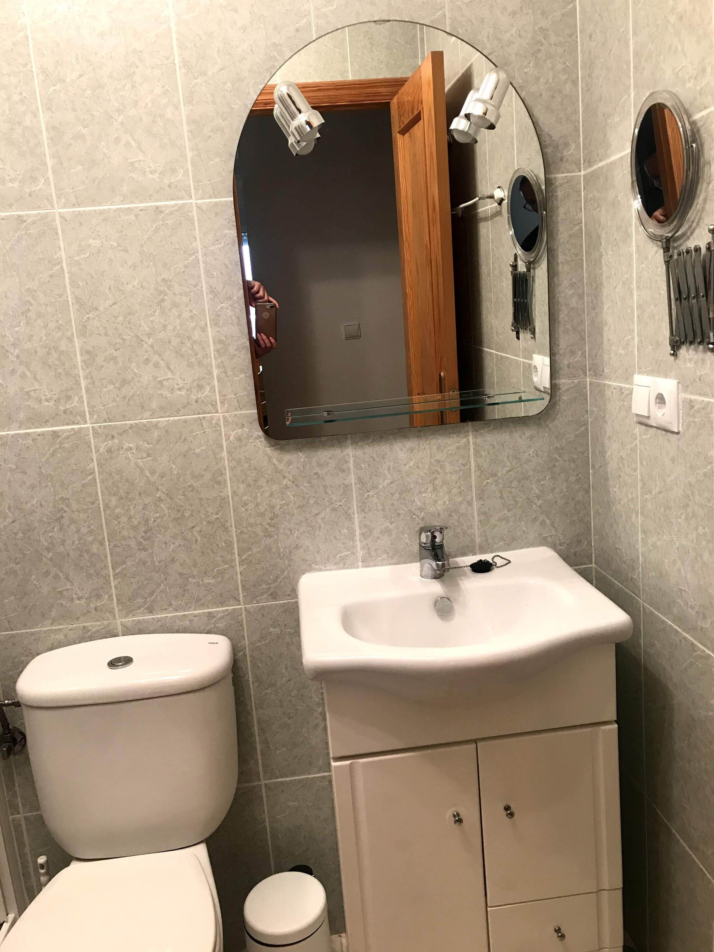 Une salle de bain avec des toilettes, un lavabo et un miroir.