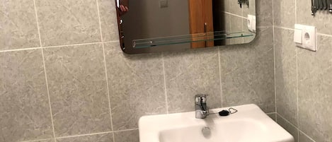 A bathroom with a toilet, sink, and mirror.