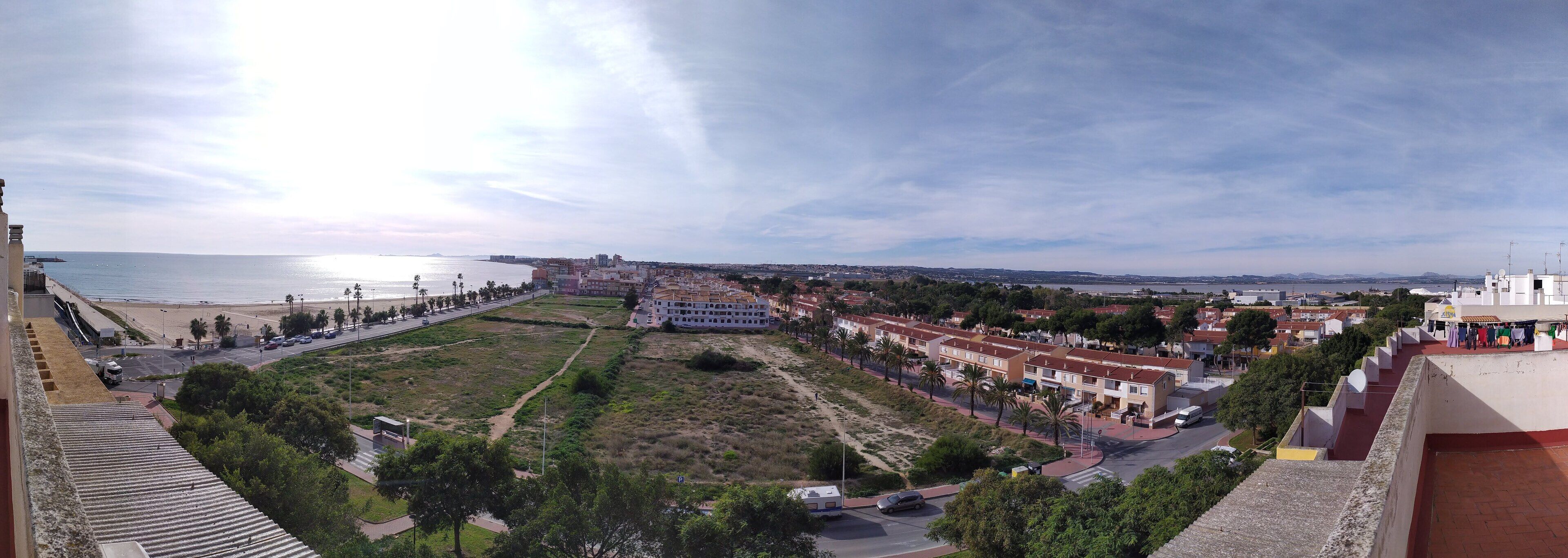 A coastal cityscape with a beach, a large building, and residential areas.