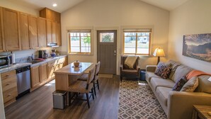 A spacious kitchen with wooden cabinets, a dining area with a table and chairs, a sofa with a patterned rug, and a door leading outside. - Views! 1Blk to Town, Clean+Charming,pets ok-Middle (Sisters)