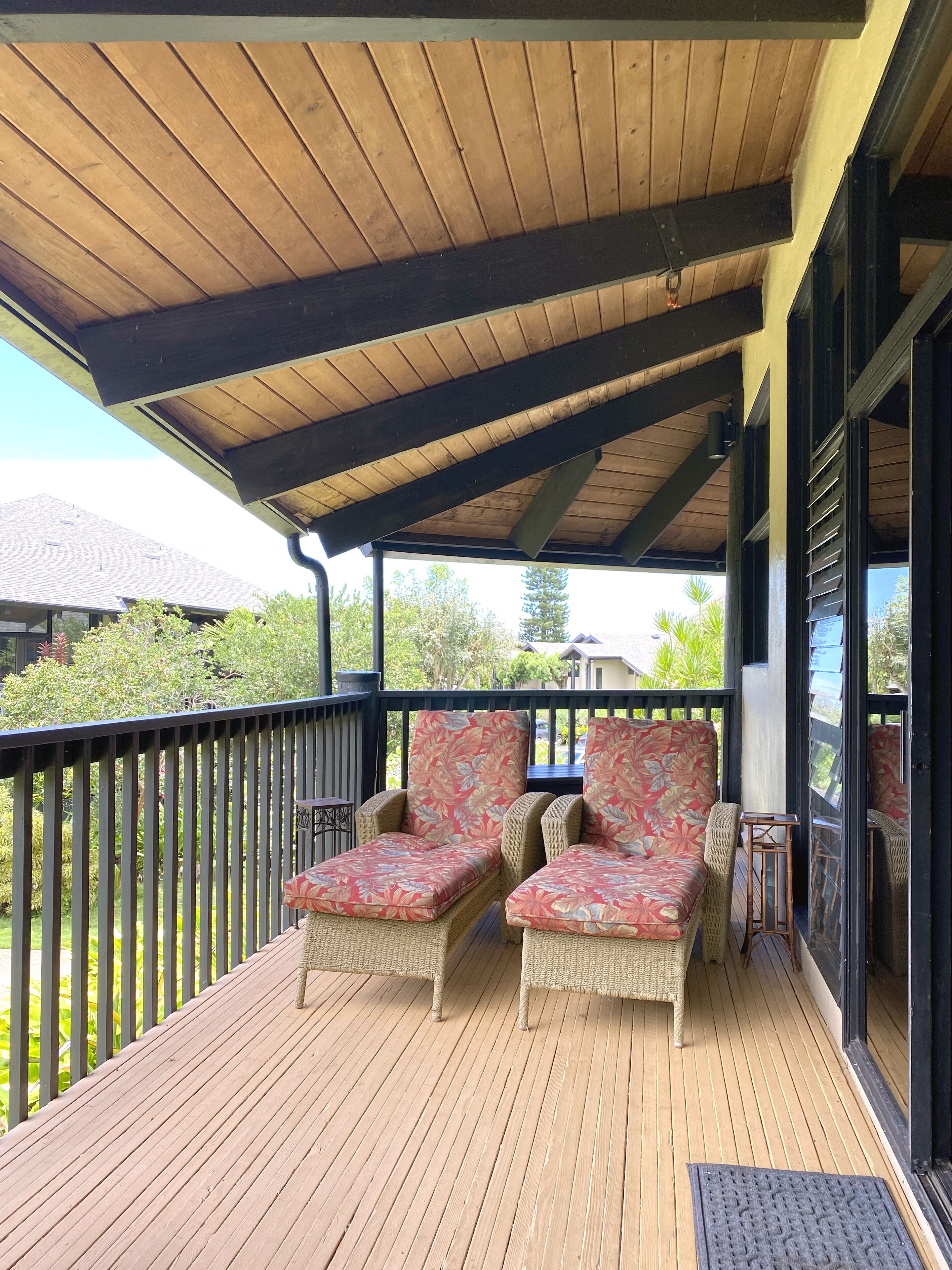 A covered outdoor seating area with wicker furniture and a wooden deck.