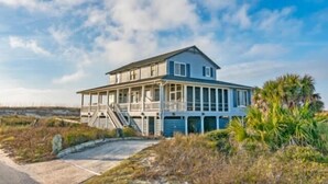 A two-story beachfront house with a covered porch and a staircase leading to the upper level. - Ocean view home, remodeled with large bedrooms and living space! Wrap around porches for enjoyment (Bald Head Island)