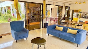 A modern living room with a blue sofa, a matching armchair, and a small coffee table. -  KIA ORA LODGE (Assinie)
