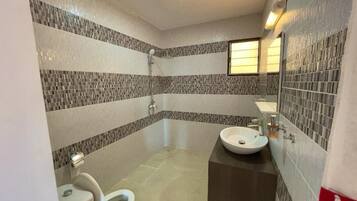 A bathroom with a toilet, sink, and shower.
