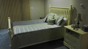 A bedroom with a bed, a nightstand, a lamp, and a radiator. - --------------------------------- (Toms River)