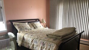 A bedroom with a bed, a nightstand, a lamp, and a window with blinds. - --------------------------------- (Toms River)