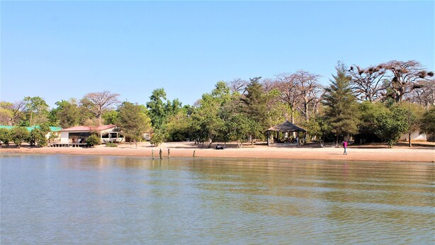 A calm lake with a gazebo and a building on the shore. - Jerreh Camp Lodge (Sittanunku)