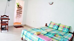 A bedroom with a bed, a chair, a small rug, and a wall-mounted plant. - Jerreh Camp Lodge (Sittanunku)