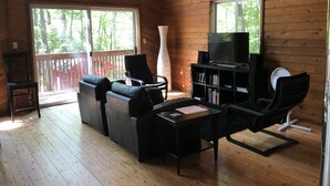 A wooden cabin with a TV, seating area, and large windows. - Cottage in the Woods (Grand Bend)