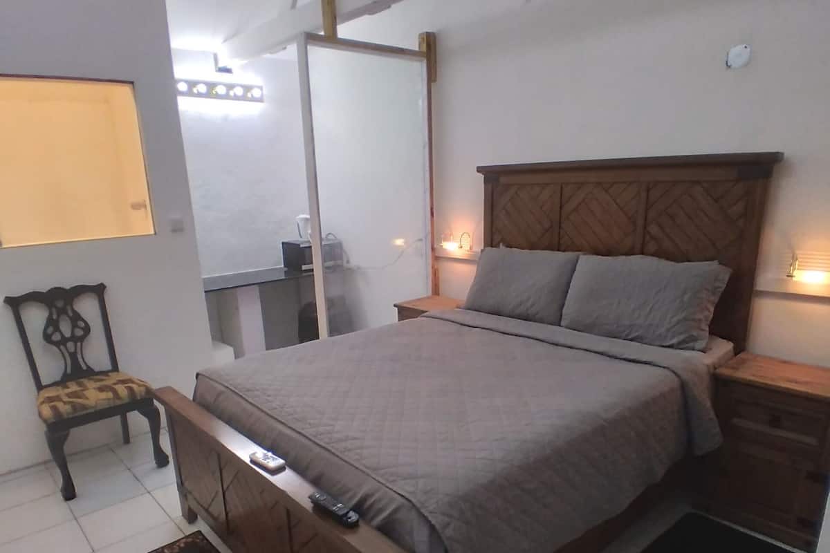 Une chambre à coucher comprenant un lit, des tables de chevet, une chaise, un bureau et un miroir.