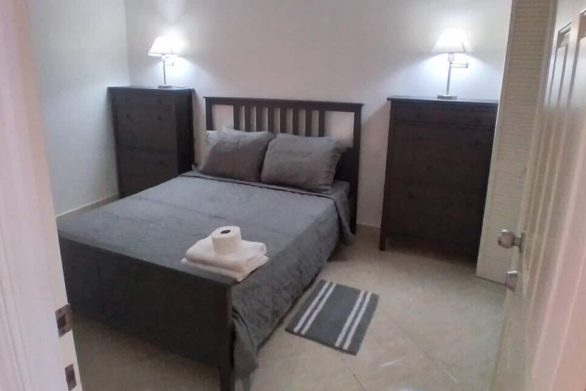 Une chambre à coucher avec un lit, deux lampes de chevet, un ventilateur de plafond et une porte.