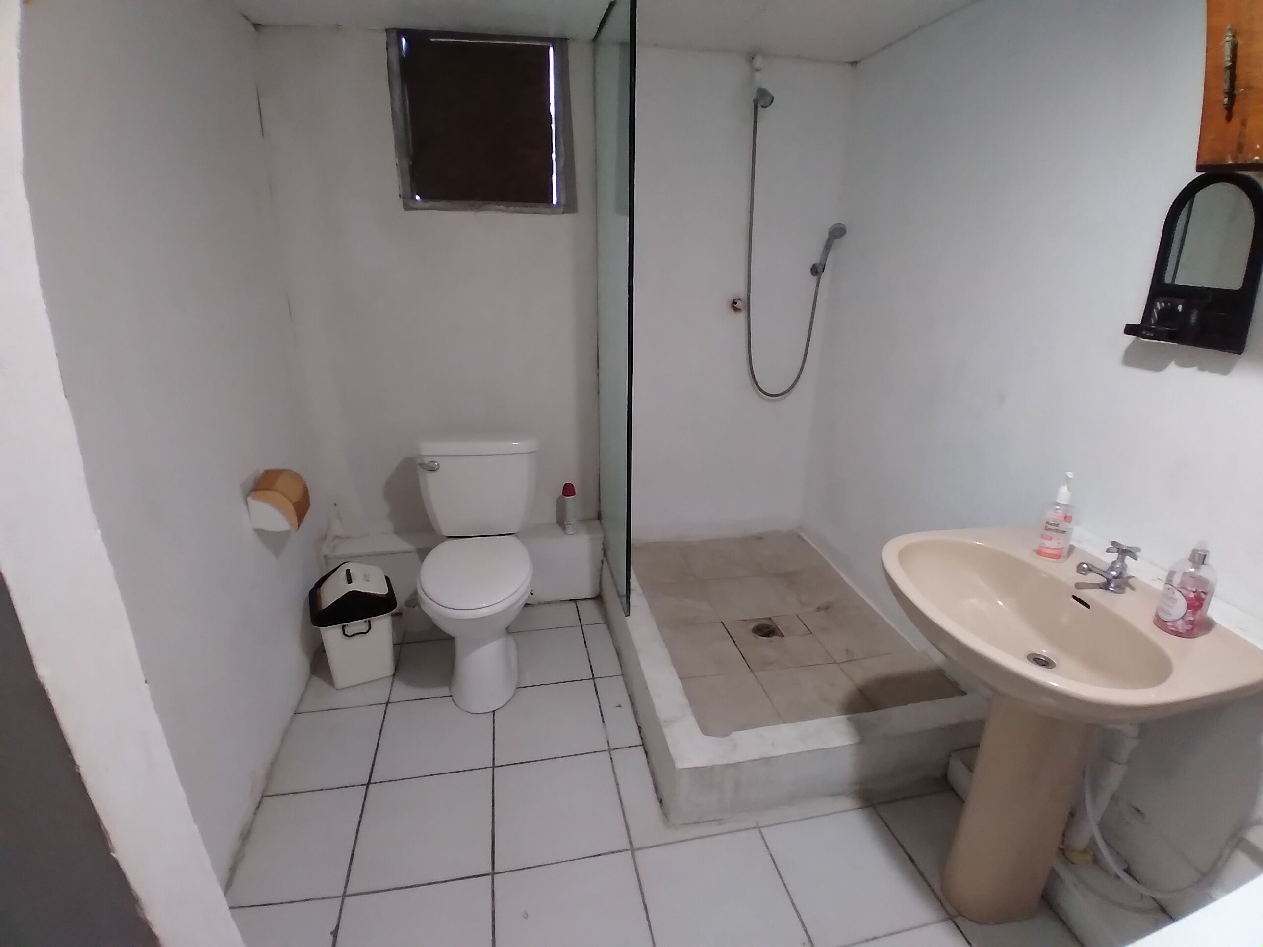 Un baño pequeño con inodoro, ducha y lavamanos.