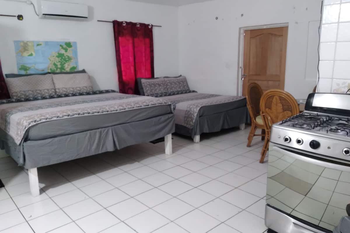Une chambre avec deux lits, une chaise en bois, un poêle et une carte accrochée au mur.