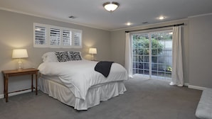 A bedroom with a large bed, two bedside tables with lamps, a window with curtains, and a view of greenery outside. - Oakway Blissful Abode, Walk to Autzen Stadium (Eugene)