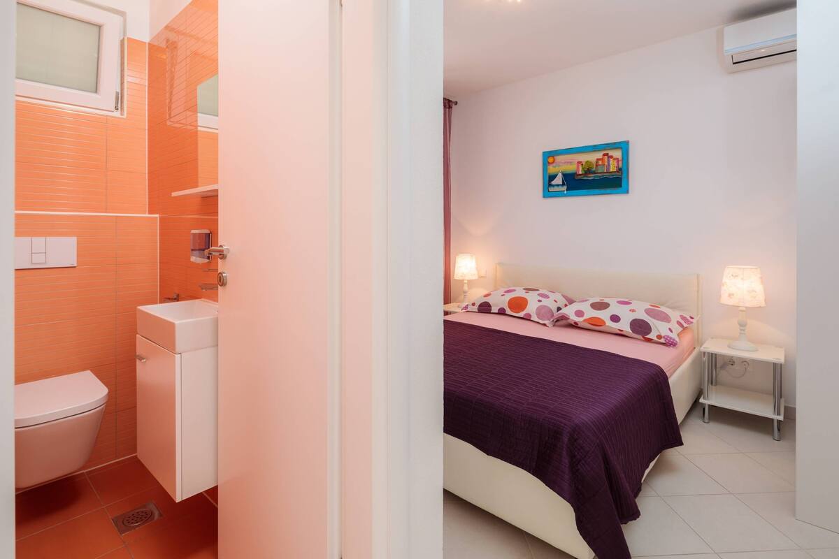 A bedroom with a bed, pillows, a nightstand, and a wall-mounted picture.