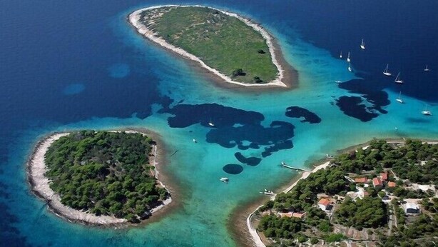 An aerial view of a coastal area with three small islands, clear blue waters, and a few boats. - Gem of the Sea Alenka (Seget)