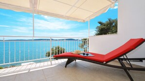 A balcony with a red lounge chair, a white umbrella, and a view of the sea. - Gem of the Sea Alenka (Seget)