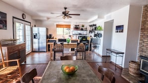 A spacious kitchen with a dining area, wooden furniture, and a ceiling fan.
