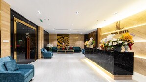 A hotel reception area with a marble reception desk, blue armchairs, and a large wall mural.
