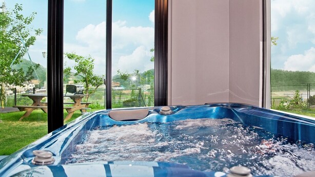Ein Whirlpool mit freiem Blick auf einen Garten und einem Picknicktisch.