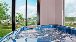Un jacuzzi con vista despejada a un jardín y una mesa de picnic en el exterior.