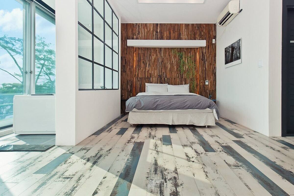 A bedroom with a bed, a wooden wall, a window, and a door.