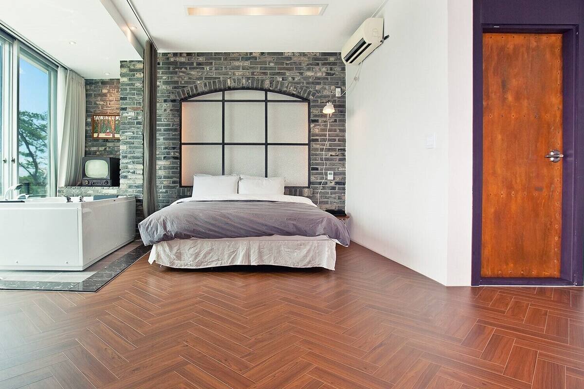 A modern bedroom with a large bed, a built-in bathtub, and a view of the outdoors.