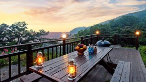 Eine Holzterrasse mit Esstisch, Grill und Laternen.
