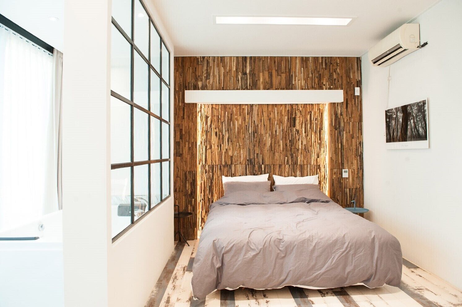 Une chambre moderne avec un grand lit, un lambris en bois, une fenêtre et un appareil de climatisation.