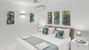 Un dormitorio moderno con cama, mesitas de noche y obras de arte en las paredes.