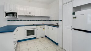 Una cocina con armarios blancos, microondas, lavavajillas y refrigerador.