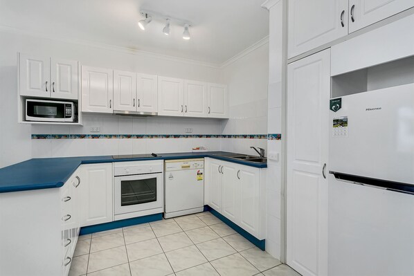 A kitchen with white cabinets, a microwave, an oven, a dishwasher, and a refrigerator.