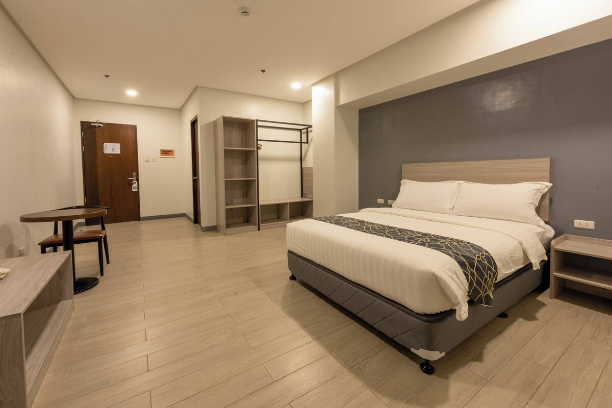 Quarto de hotel moderno com uma cama grande, uma escrivaninha e um guarda-roupa.