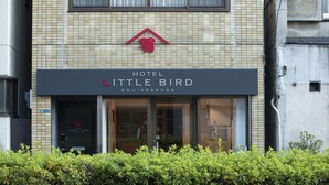 A hotel named "Hotel Little Bird" with a tiled facade and a logo above the entrance.