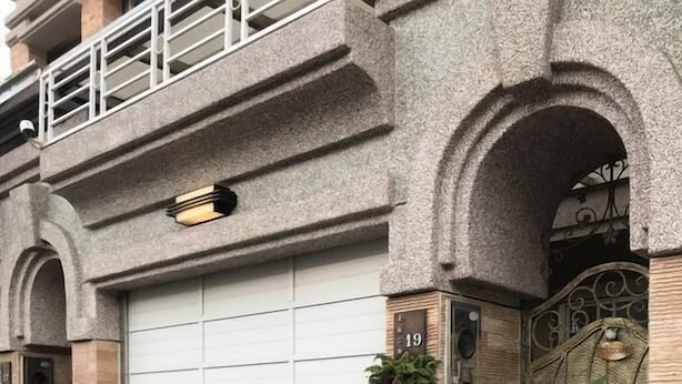 A residential building with a garage door, number 19, potted plants, and a decorative gate.