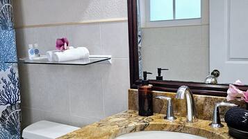 A bathroom with a marble sink, a mirror, a toilet, and a shower curtain.