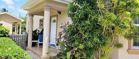 Een huis met een overdekte veranda, een witte deur en een blauwe stoel.