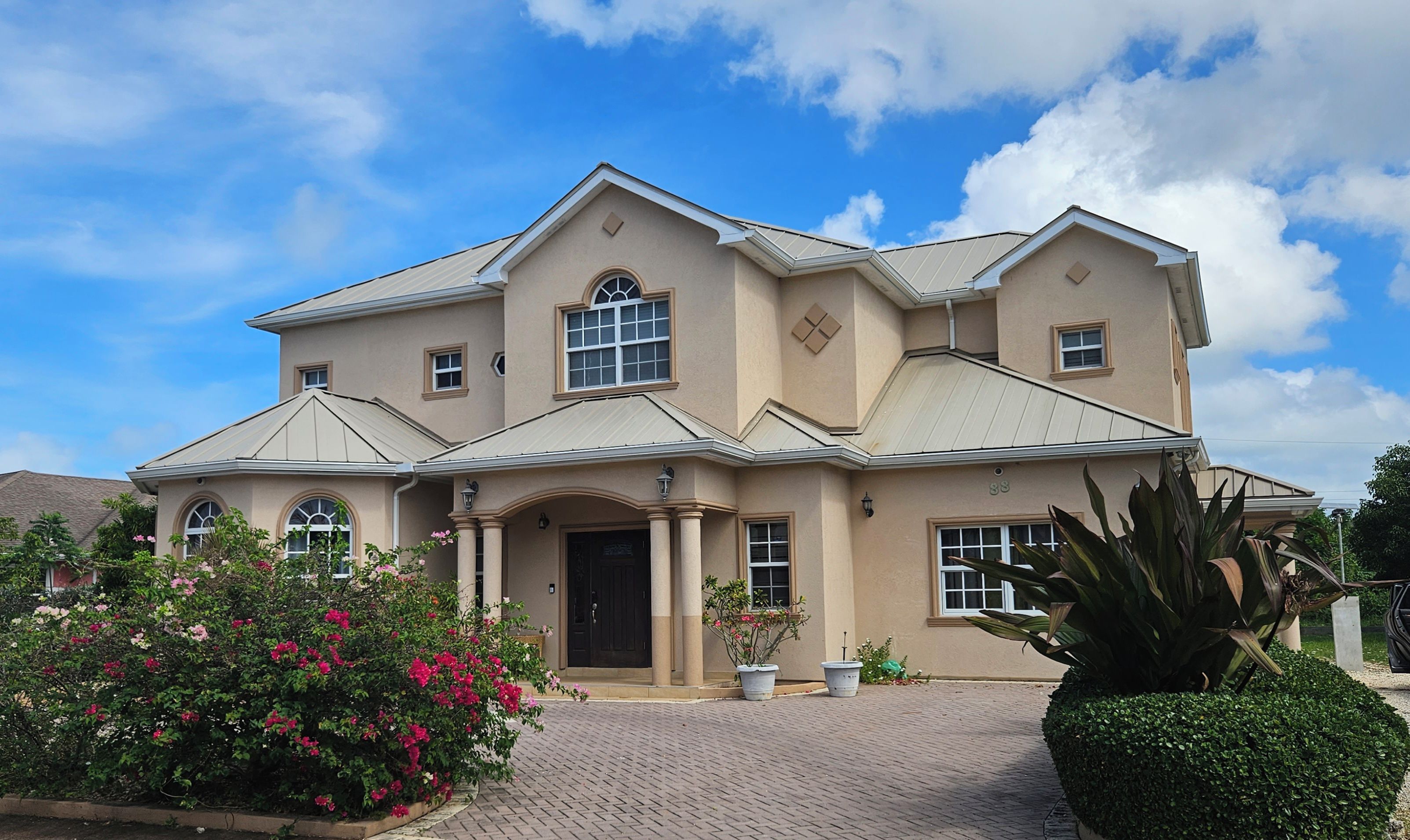 A two-story house with a symmetrical facade, a central entrance with a door, and a large window above the entrance.