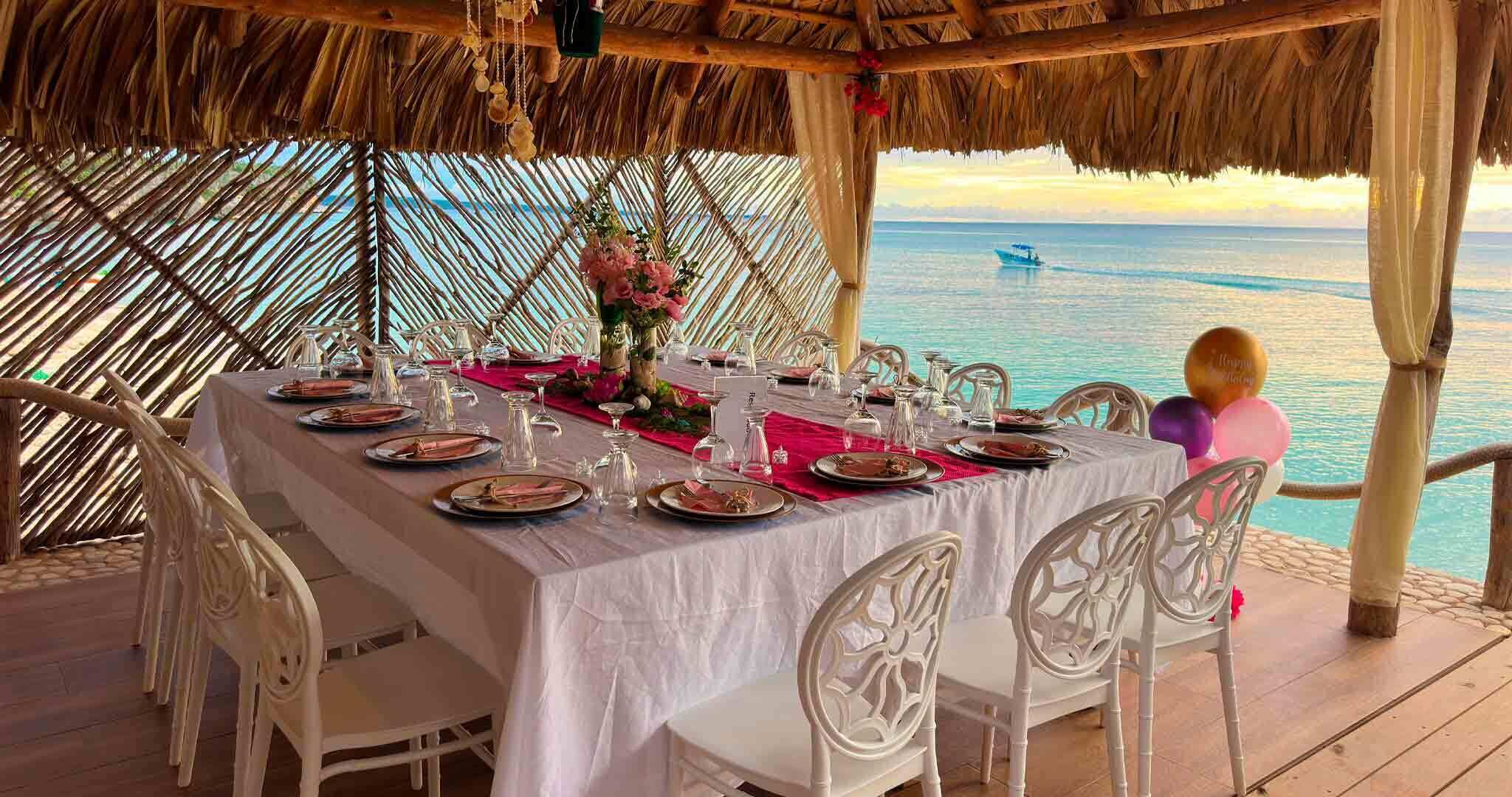 A table set for a meal with a view of the ocean and a boat in the distance.