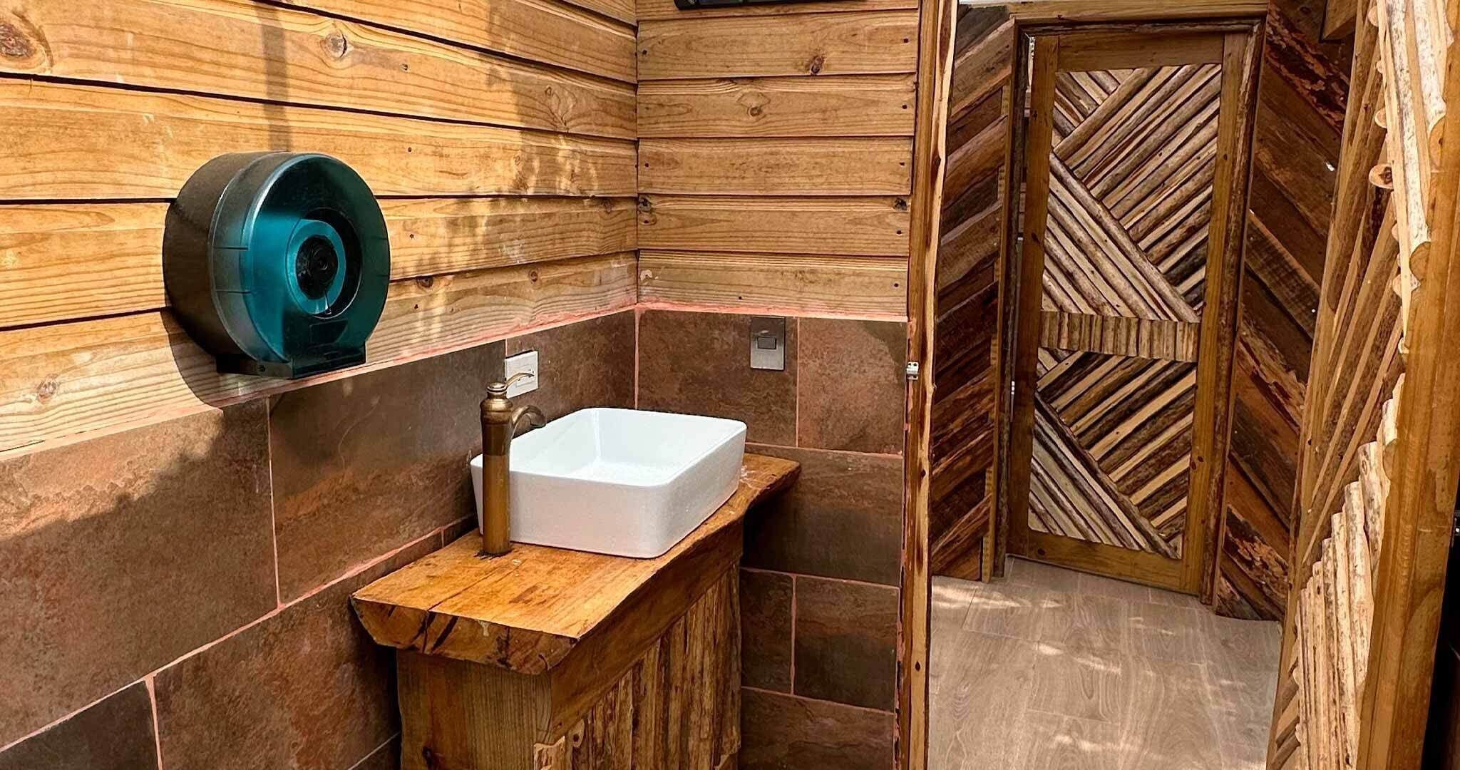 A bathroom with a wooden vanity, a white sink, and a wooden door with a chevron pattern.
