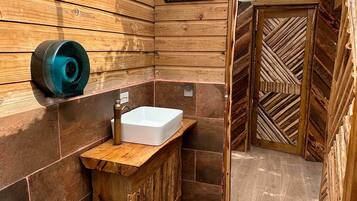 A bathroom with a wooden vanity, a white sink, and a wooden door with a chevron pattern.