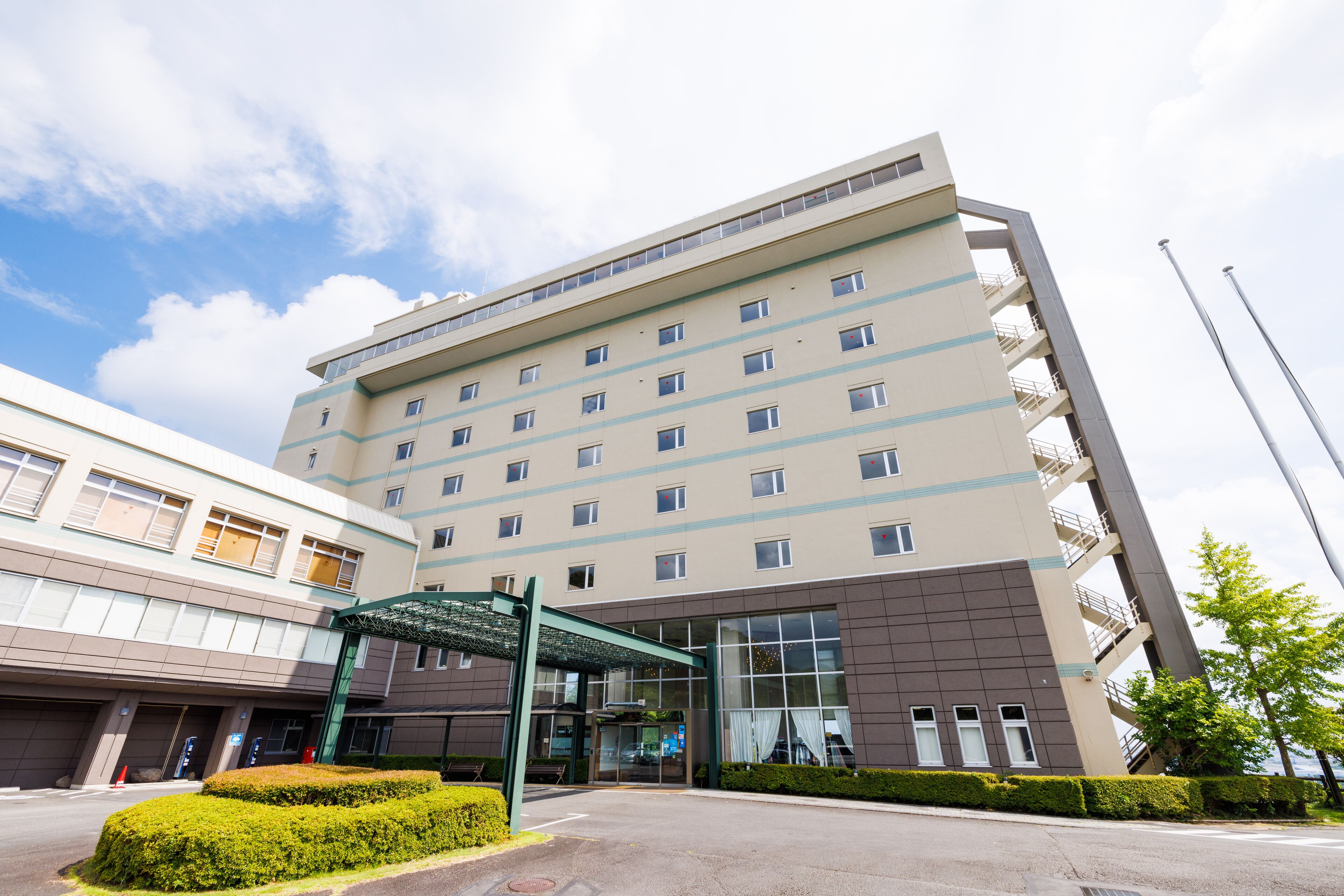 A multi-story hotel with a modern design, featuring a covered entrance and a parking area.