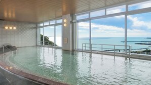 Una amplia piscina interior con vistas despejadas al océano a través de grandes ventanales.